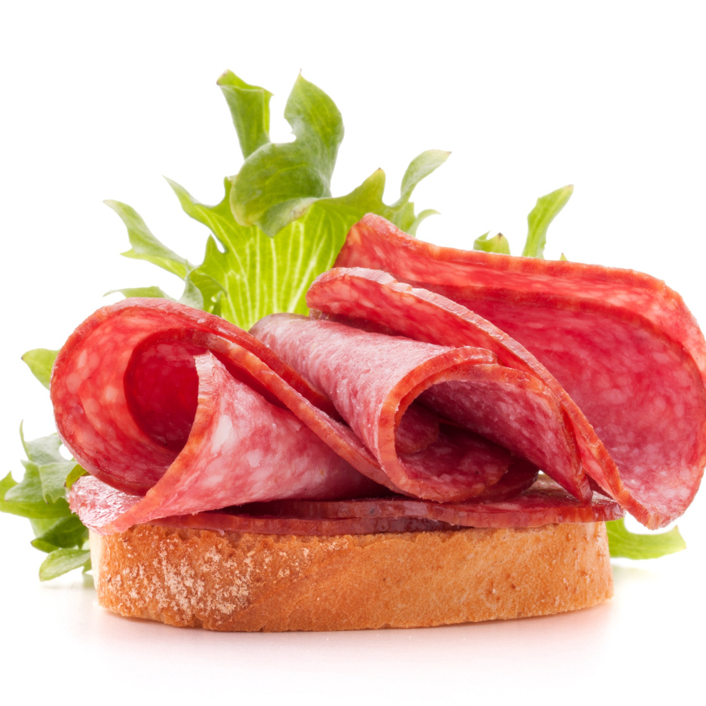 Бутерброд с листьями салата и колбасой на белом фоне