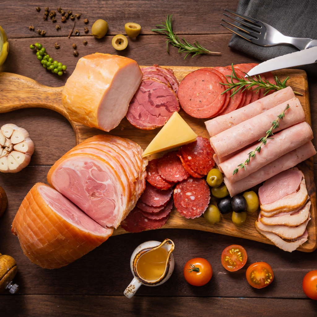 Колбасы и мясные продукты на доске со специями