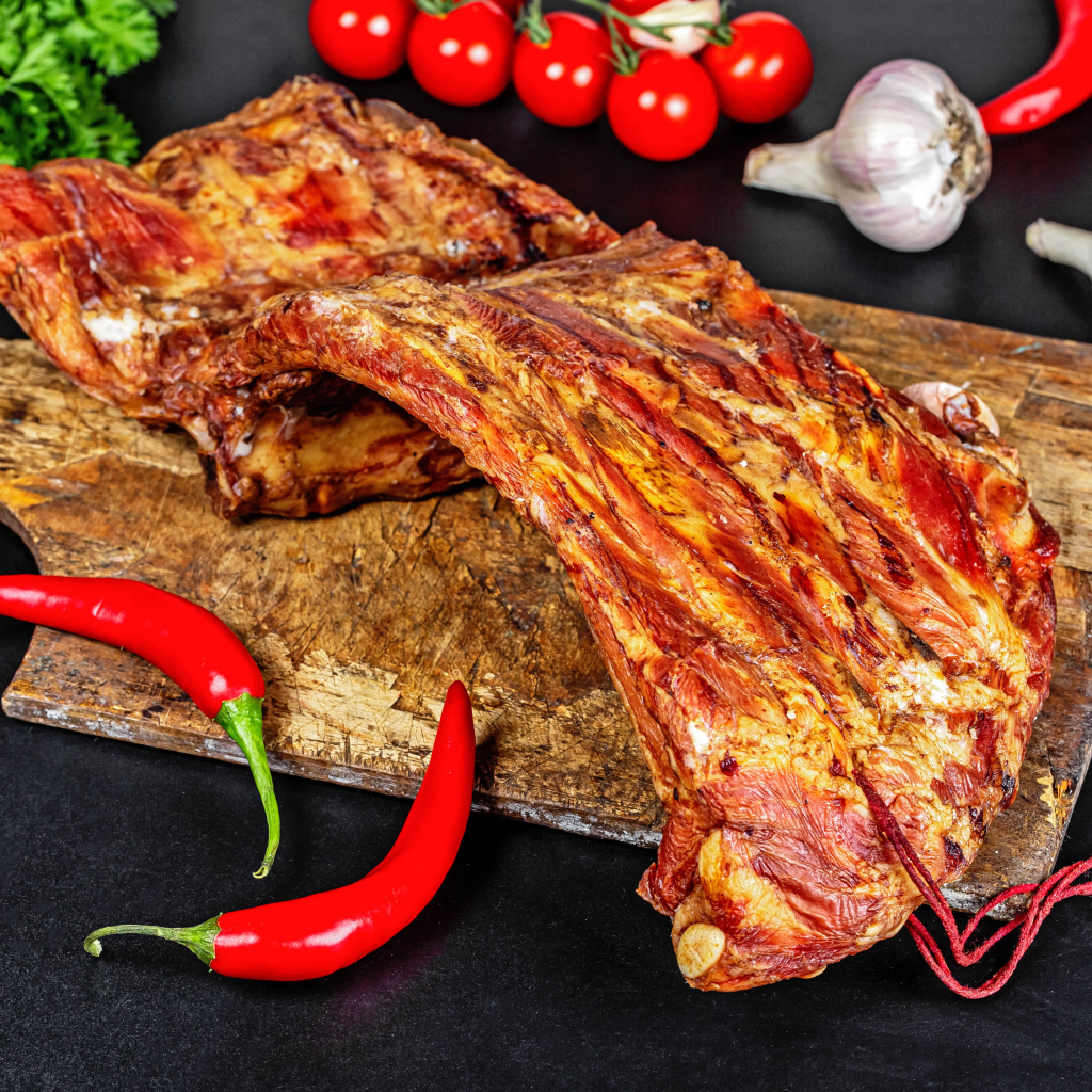 Копченые ребра на столе с красным перцем, чесноком и помидорами