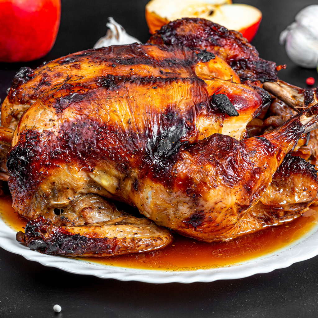 Вкусная запеченная курица на белой тарелке на столе с овощами