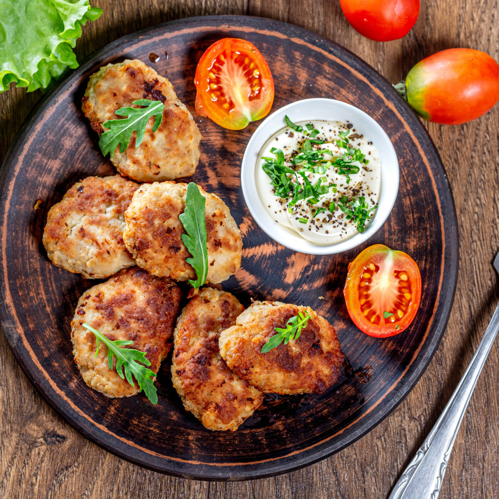 Вкусные котлеты на столе с соусом и помидорами