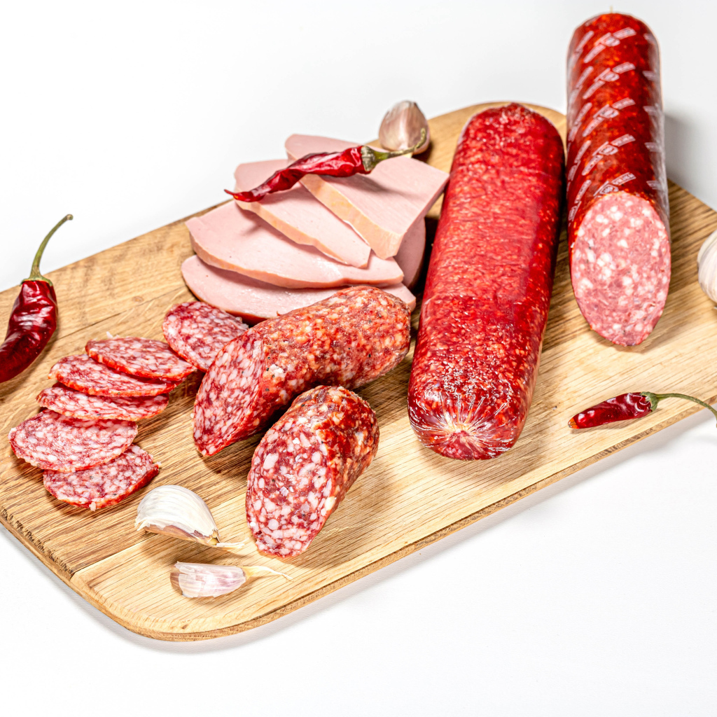 Вкусная колбаса с красным перцем и чесноком на доске на белом фоне