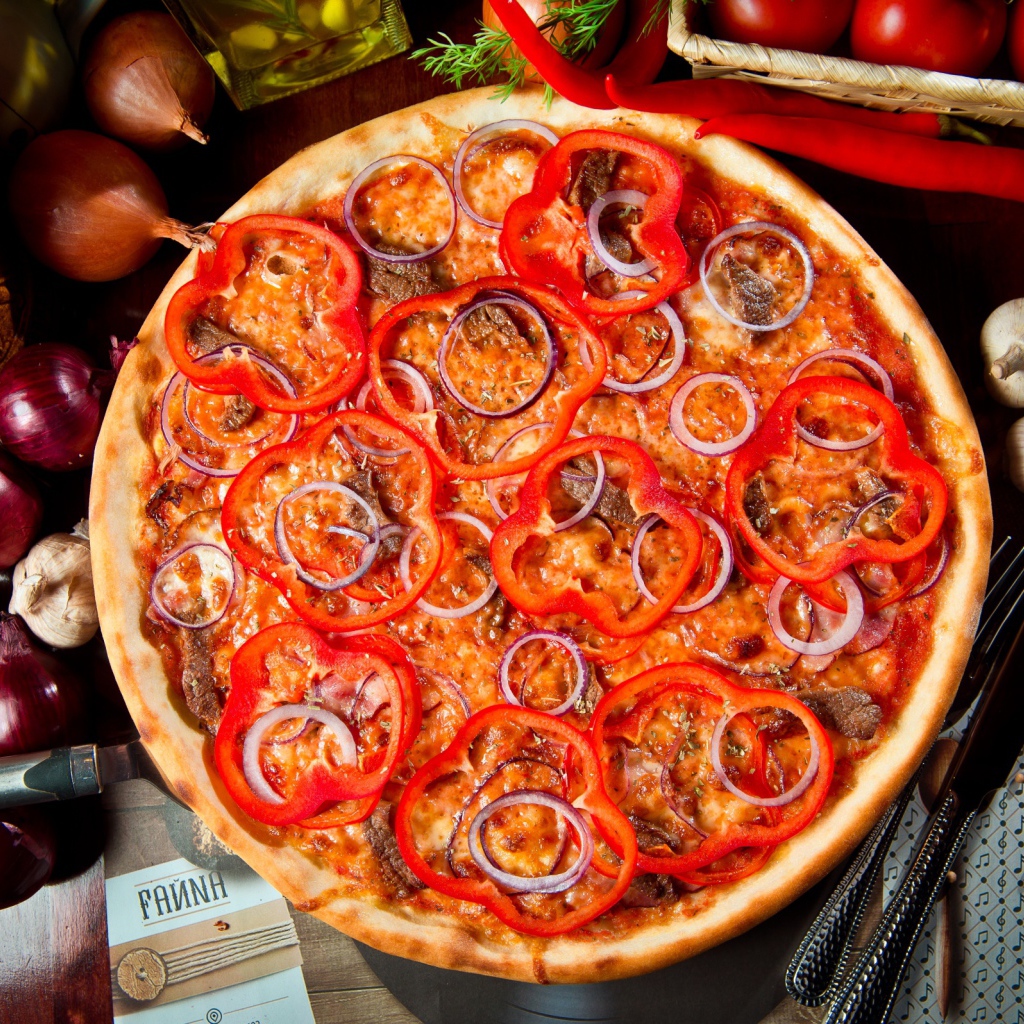 Большая пицца с мясом, луком и болгарским перцем на столе 