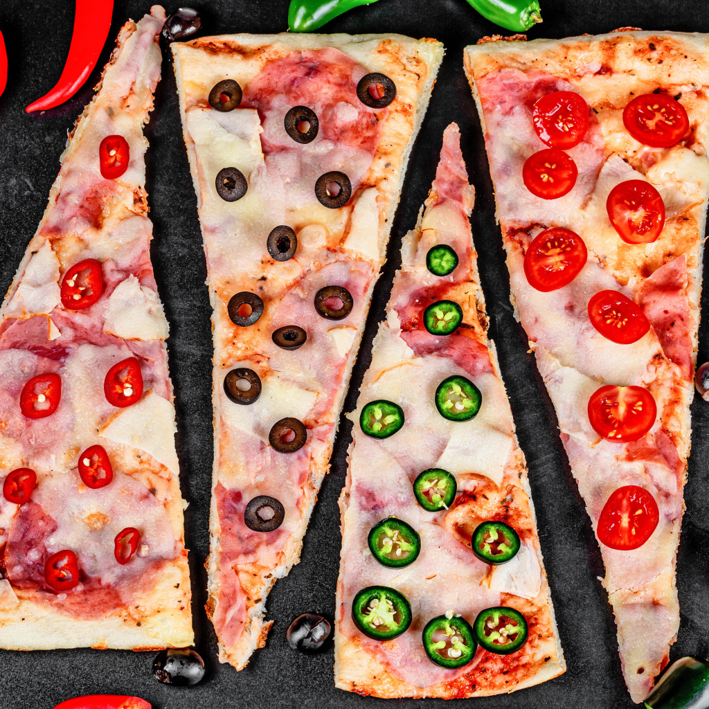 Четыре куска аппетитной пиццы с ветчиной и острым перцем