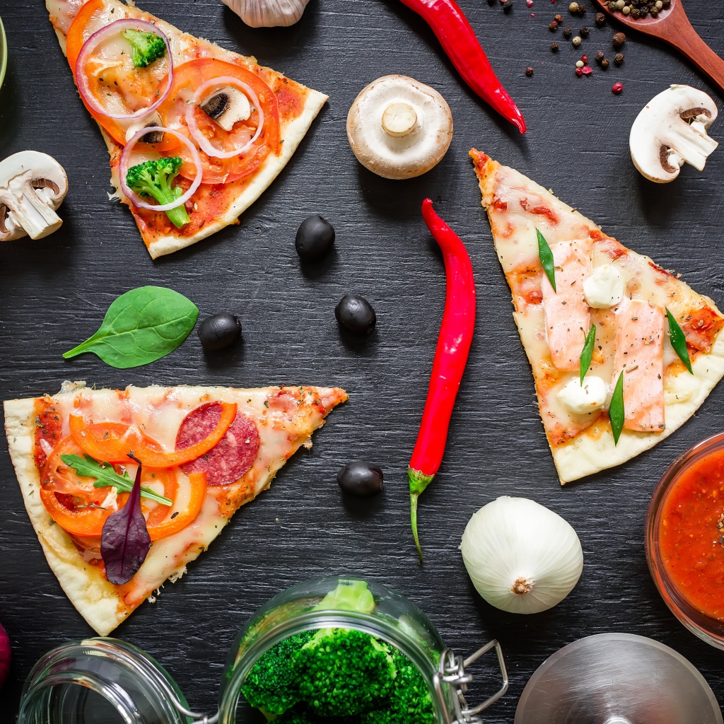 Куски пиццы на столе с овощами и соусом