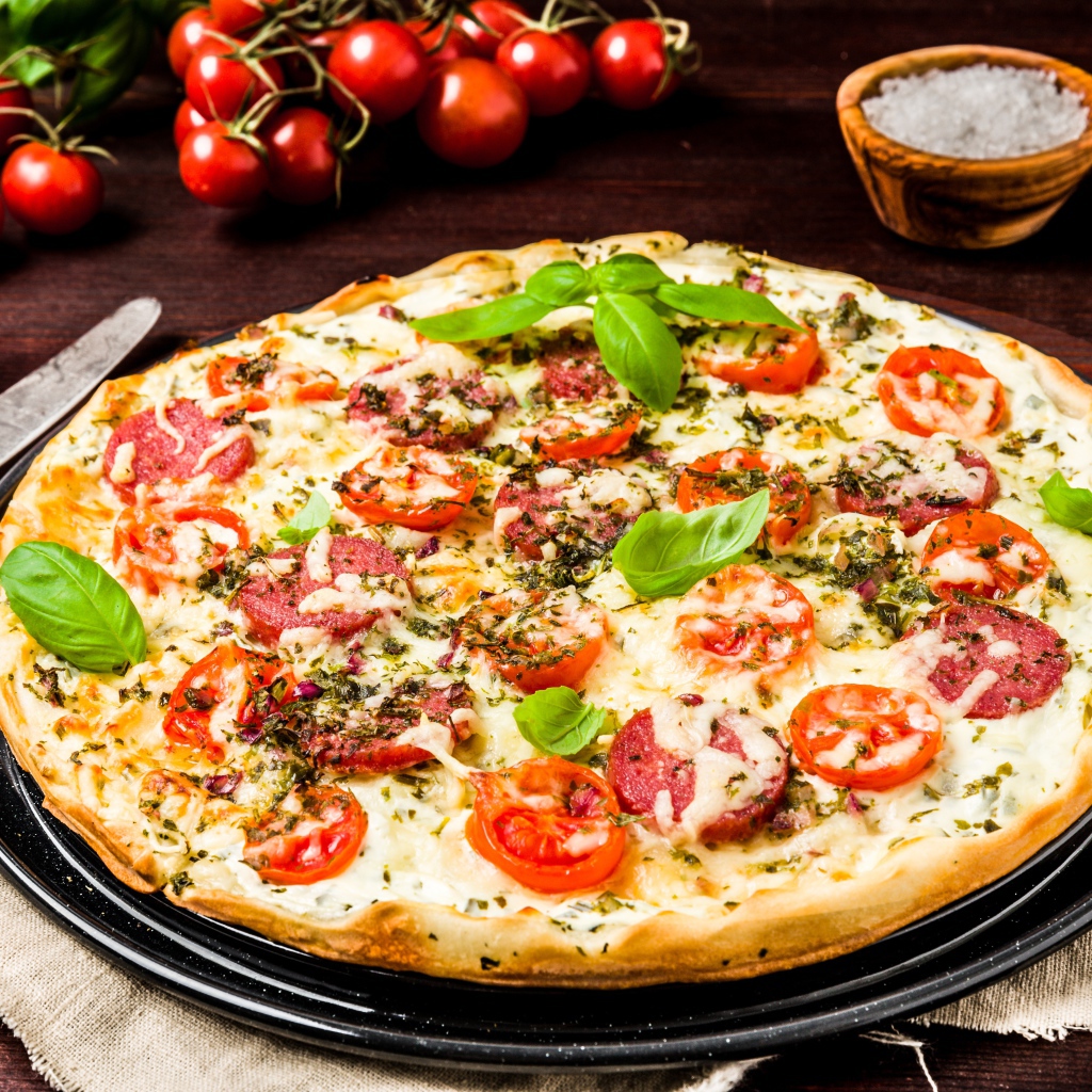 Tasty pizza with sausage, cheese and tomatoes on the table