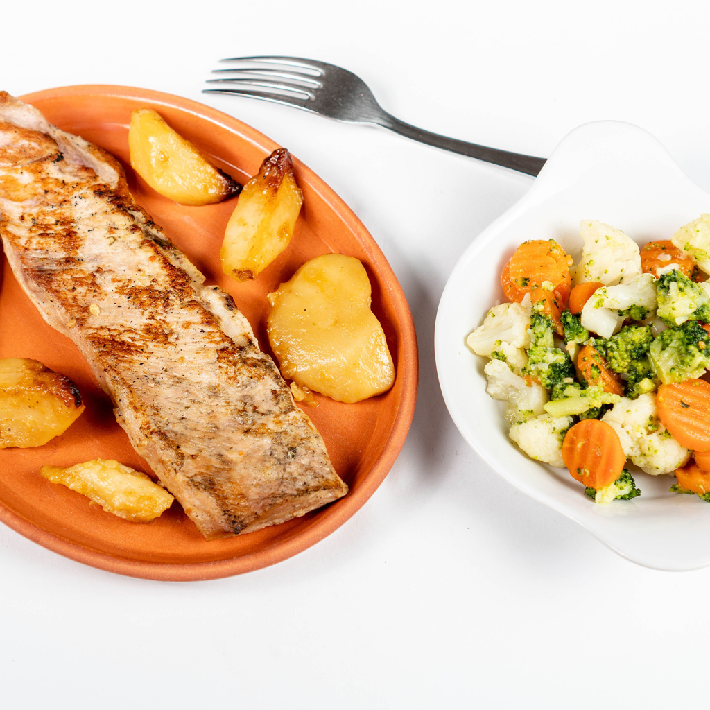 Кусок запеченной рыбы на тарелке с овощами 