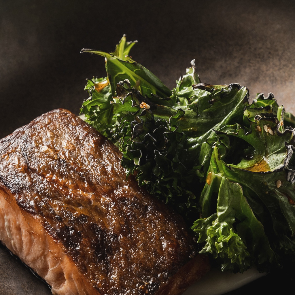 Кусок запеченной рыбы с листьями салата в сковороде 