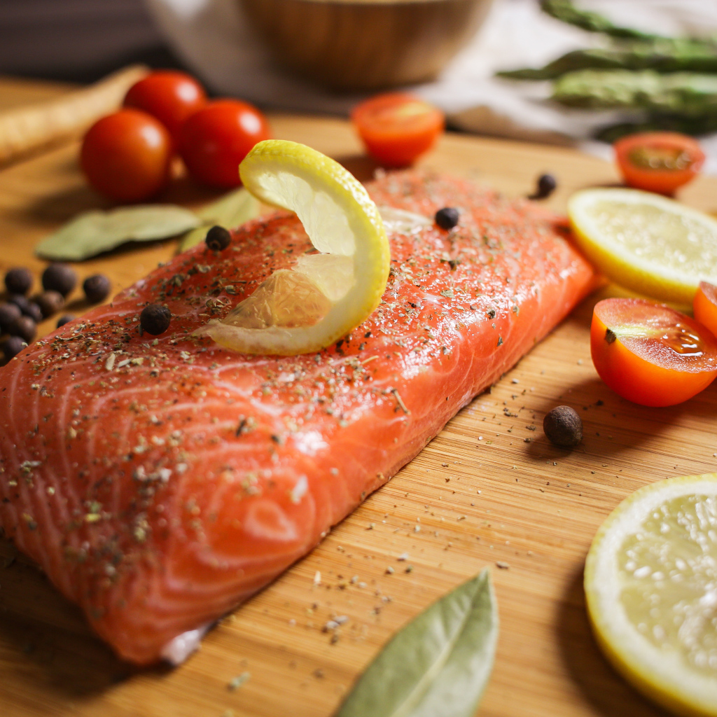 Кусок красной рыбы на доске с лимоном и помидорами