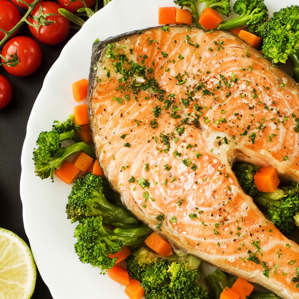 Кусок красной рыбы на тарелке с морковью и брокколи 