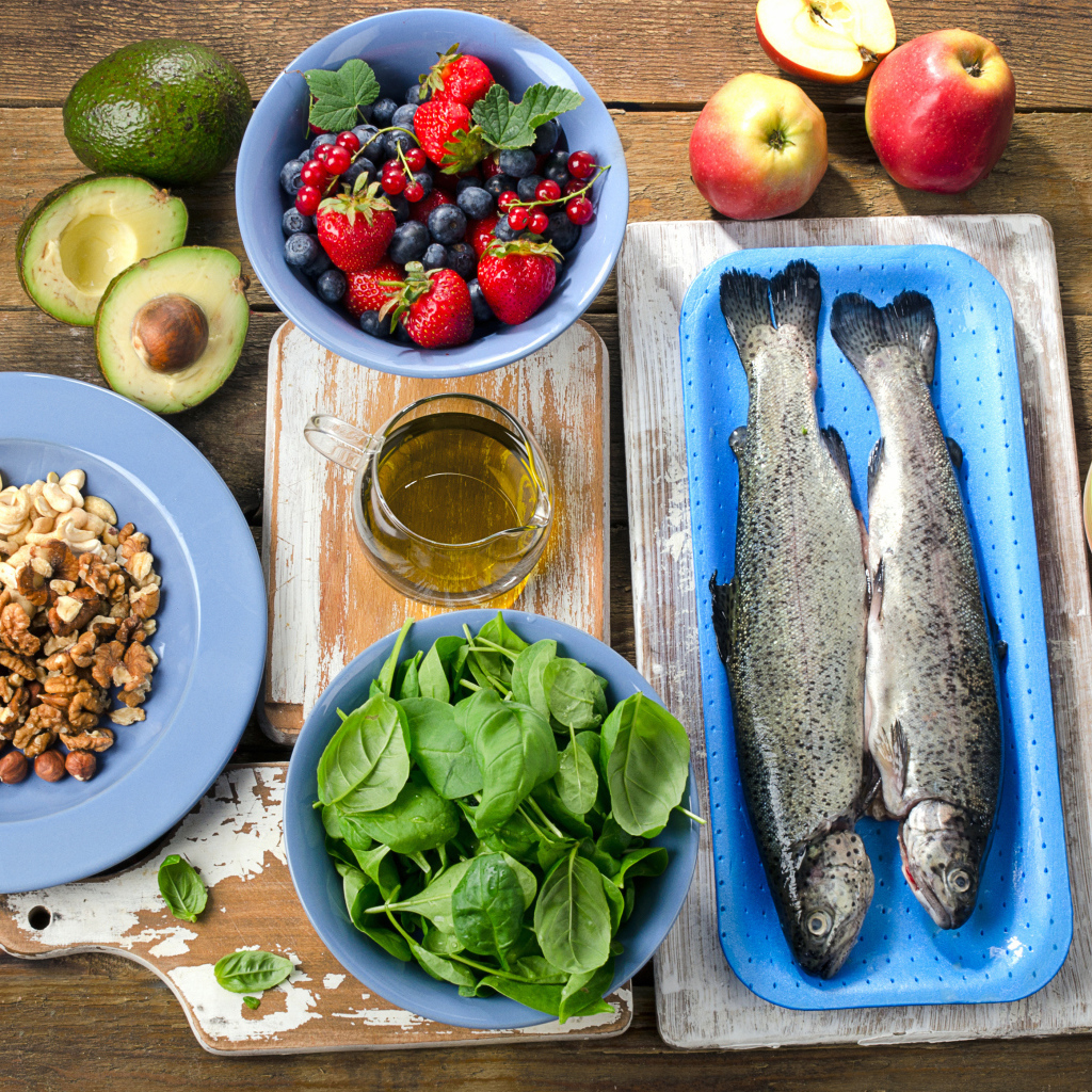 Fresh fish on a table with nuts, basil and berries