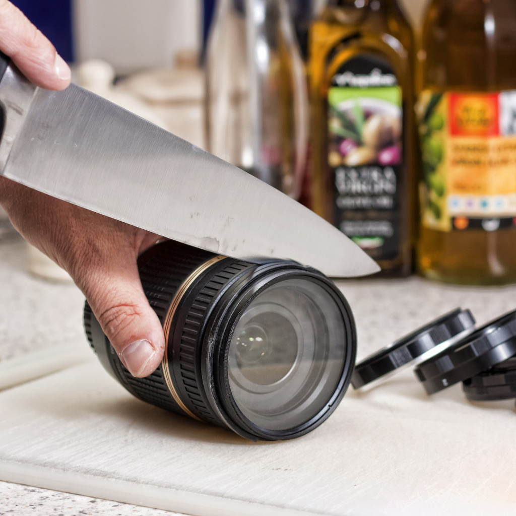 A man cuts a camera lens with a knife