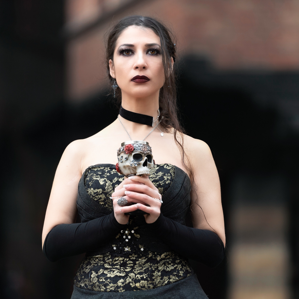 Девушка готка с бокалом - черепом в руках 