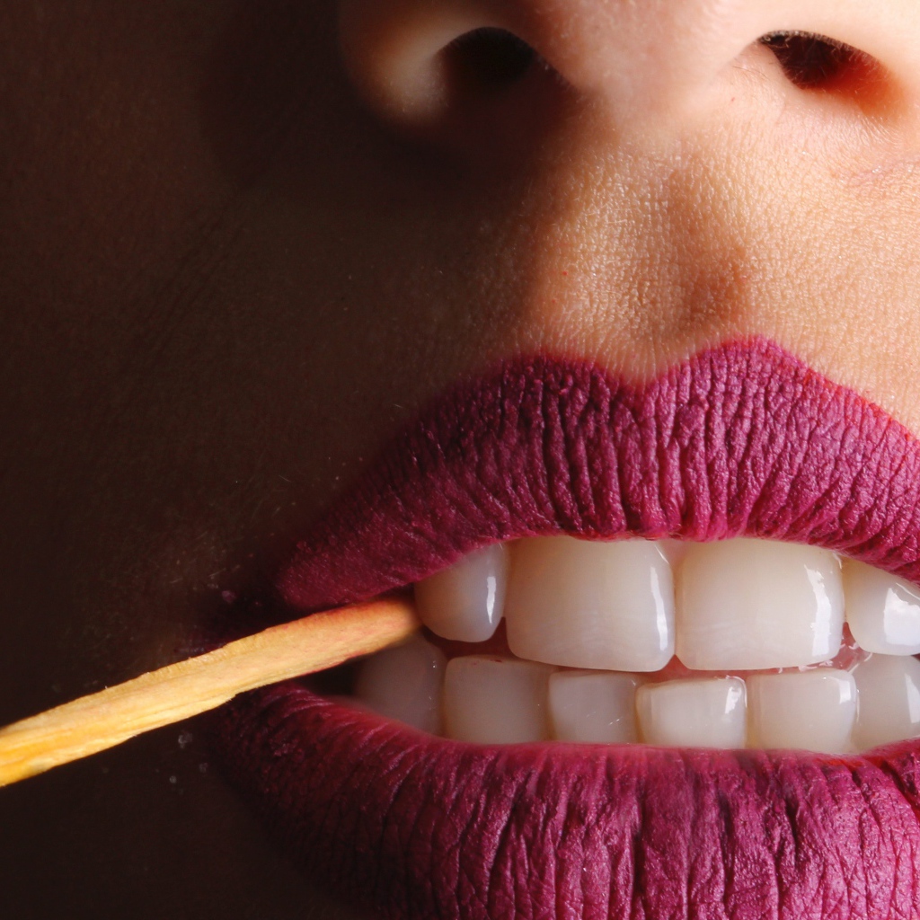 Зажженная спичка в зубах у девушки 