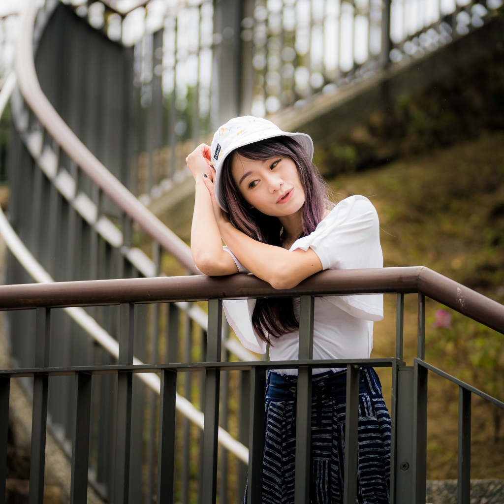 Молодая девушка азиатка стоит на лестнице у перил 