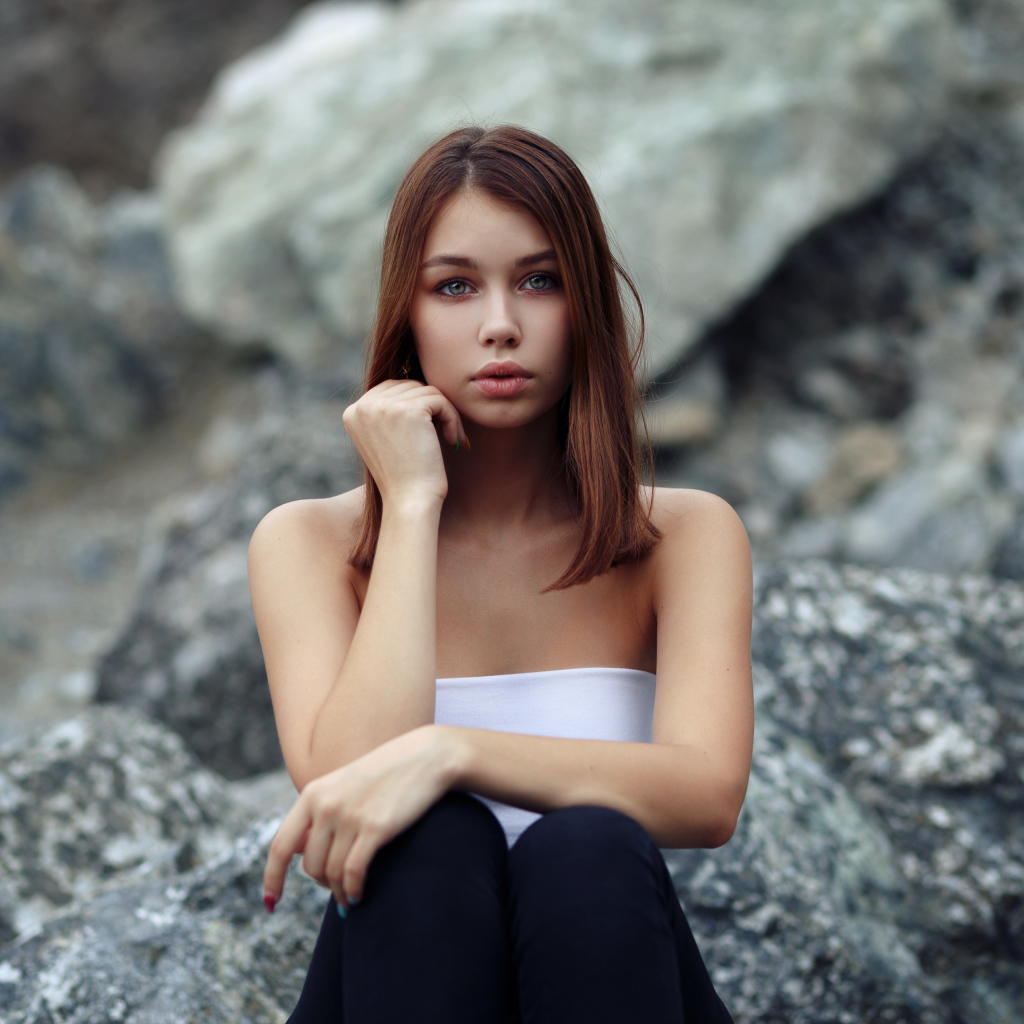 Молодая девушка сидит на камнях 