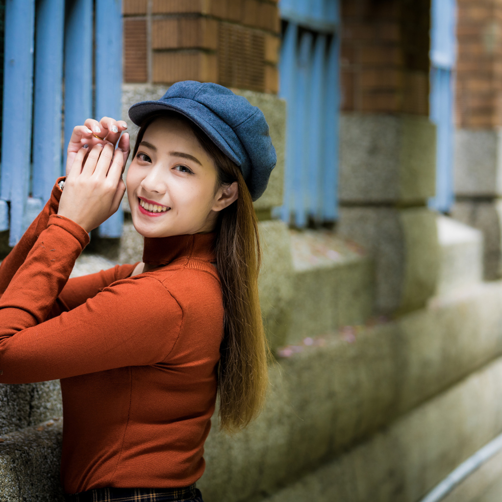 Девушка азиатка в кепке на стенке 