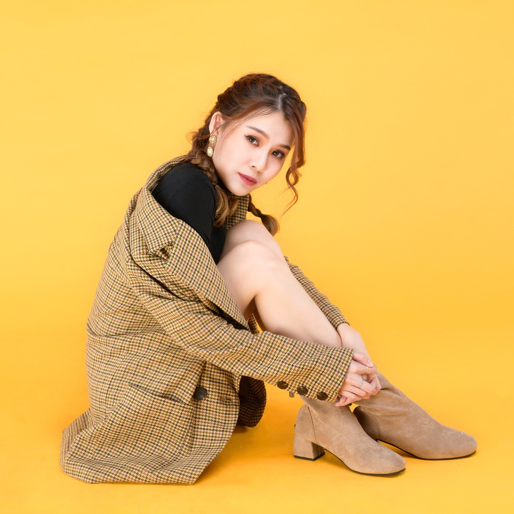 Девушка азиатка в пальто на желтом фоне 