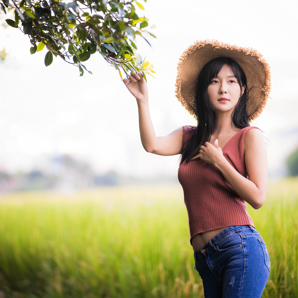 Девушка азиатка в шляпе на поле 