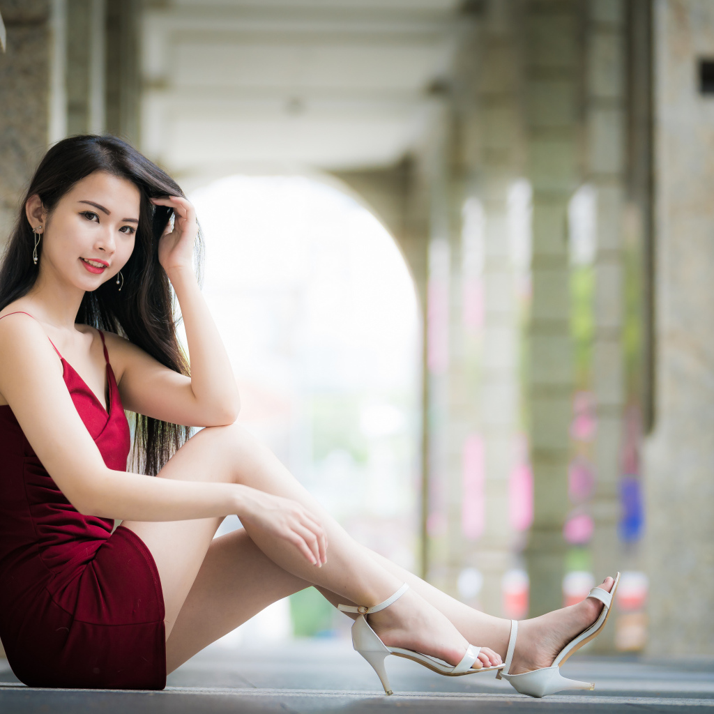 Девушка азиатка в красном платье сидит на полу