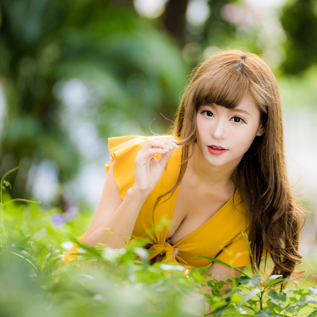 Девушка азиатка в желтом платье в парке 