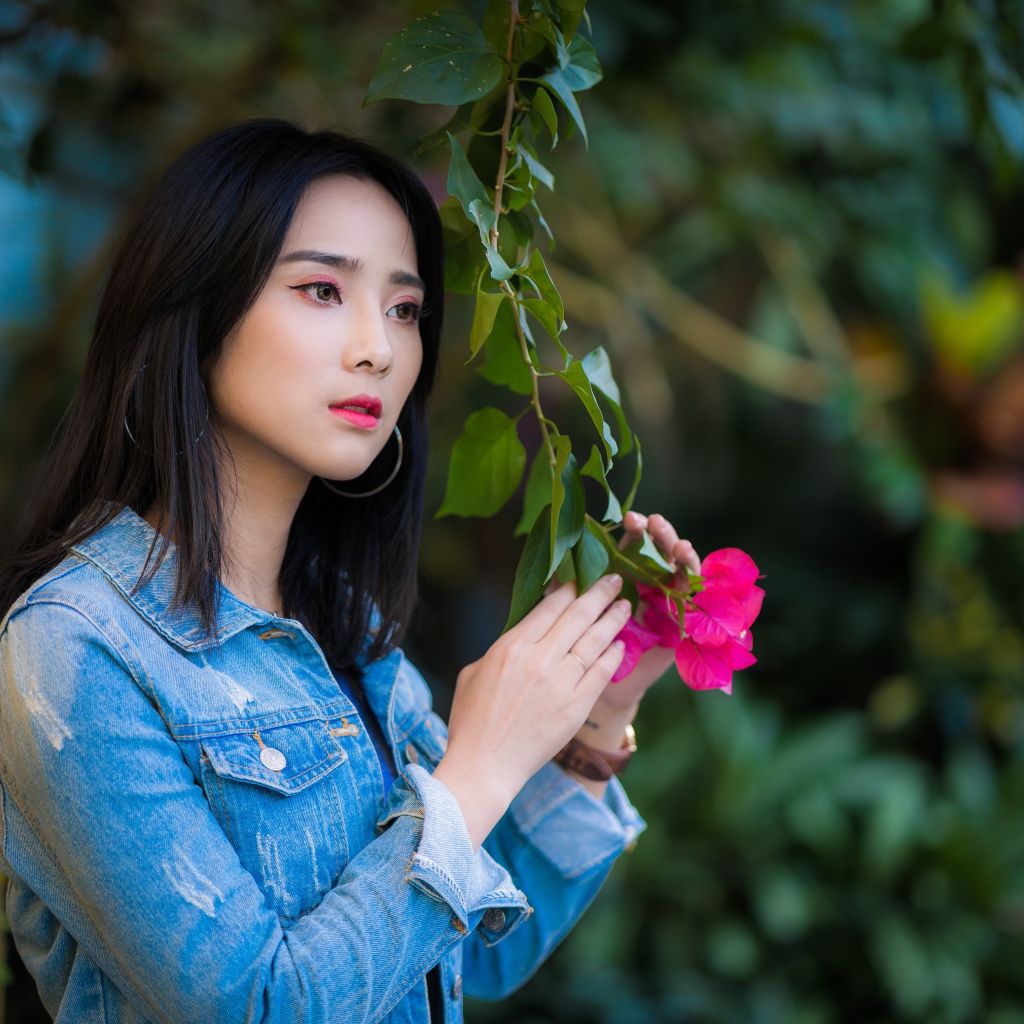 Девушка азиатка в джинсовой куртке в парке