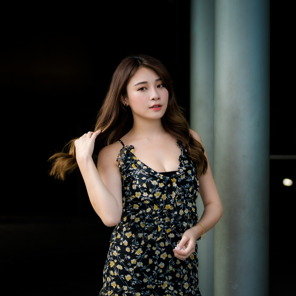 Девушка азиатка в платье трогает волосы 