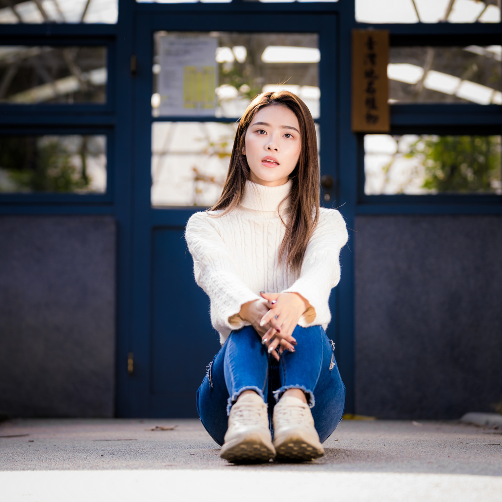 Девушка азиатка в белом свитере видит на полу 