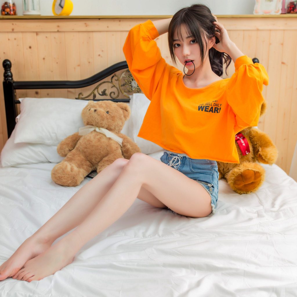 Девушка азиатка на кровати с игрушками