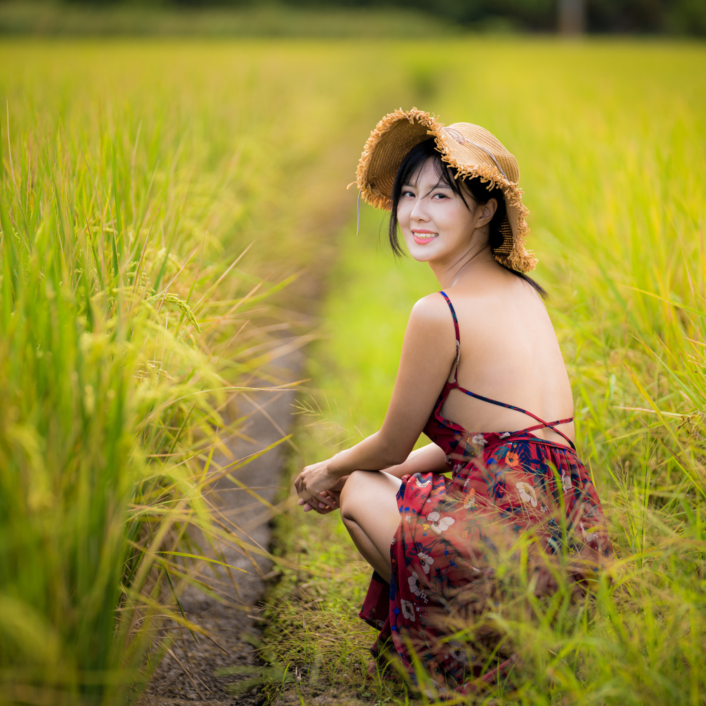Девушка азиатка сидит на рисовом поле 