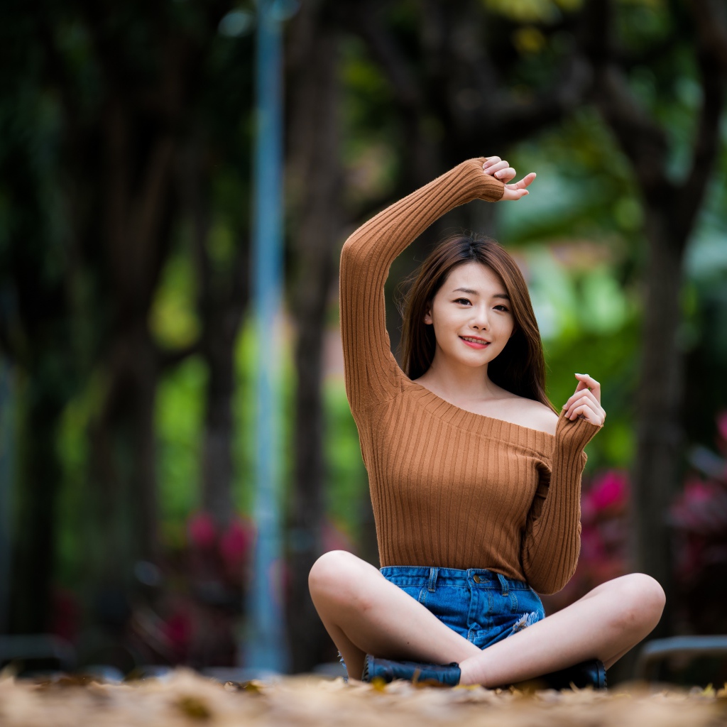 Девушка азиатка сидит в позе лотоса в парке 