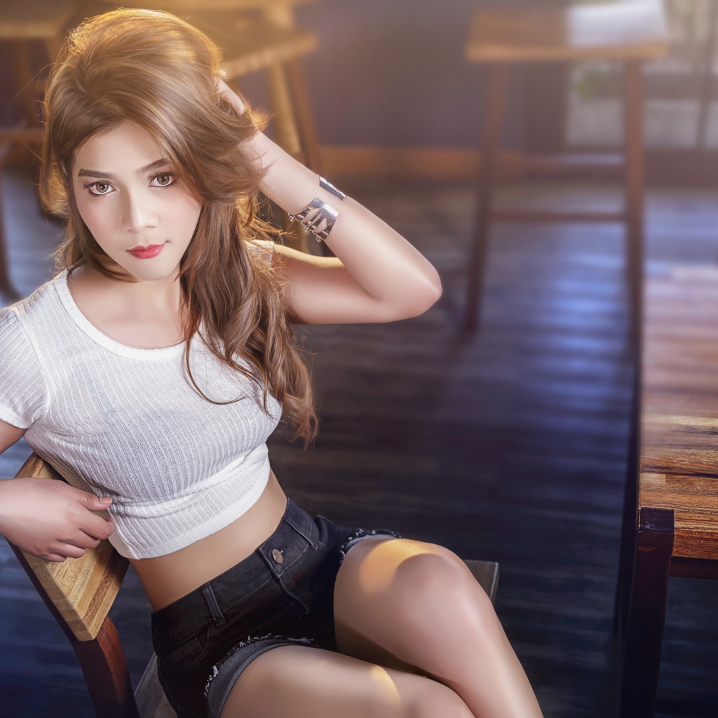 Девушка азиатка сидит на деревянном стуле в кафе