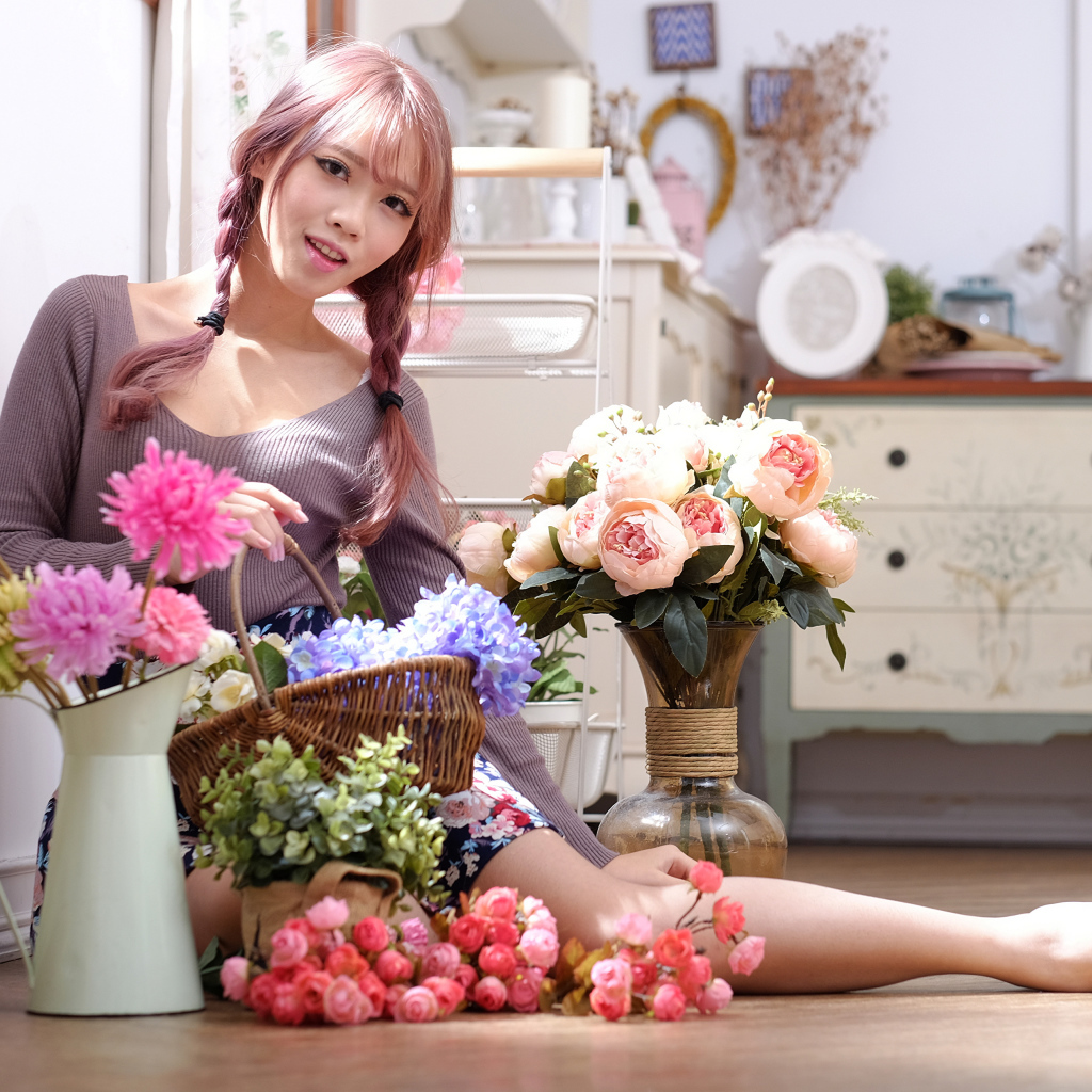 Девушка азиатка сидит с цветами на полу у окна