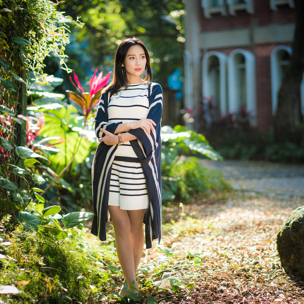 Девушка азиатка идет по улице у забора