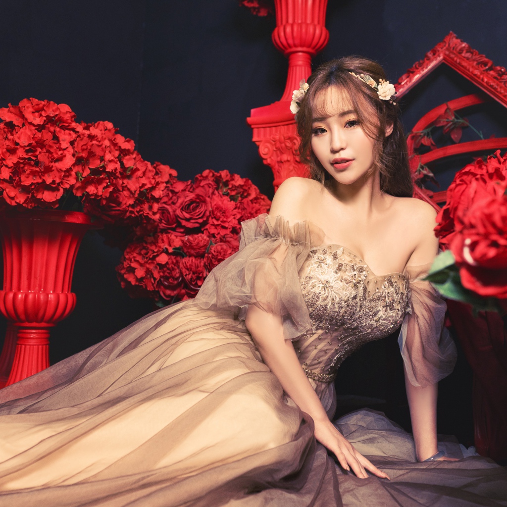 Азиатка в красивом платье в комнате с красными цветами