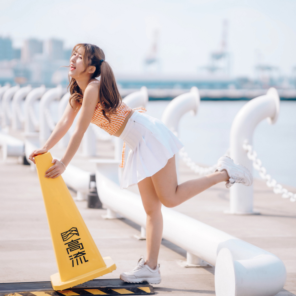 Азиатка с короткой белой юбке у воды 