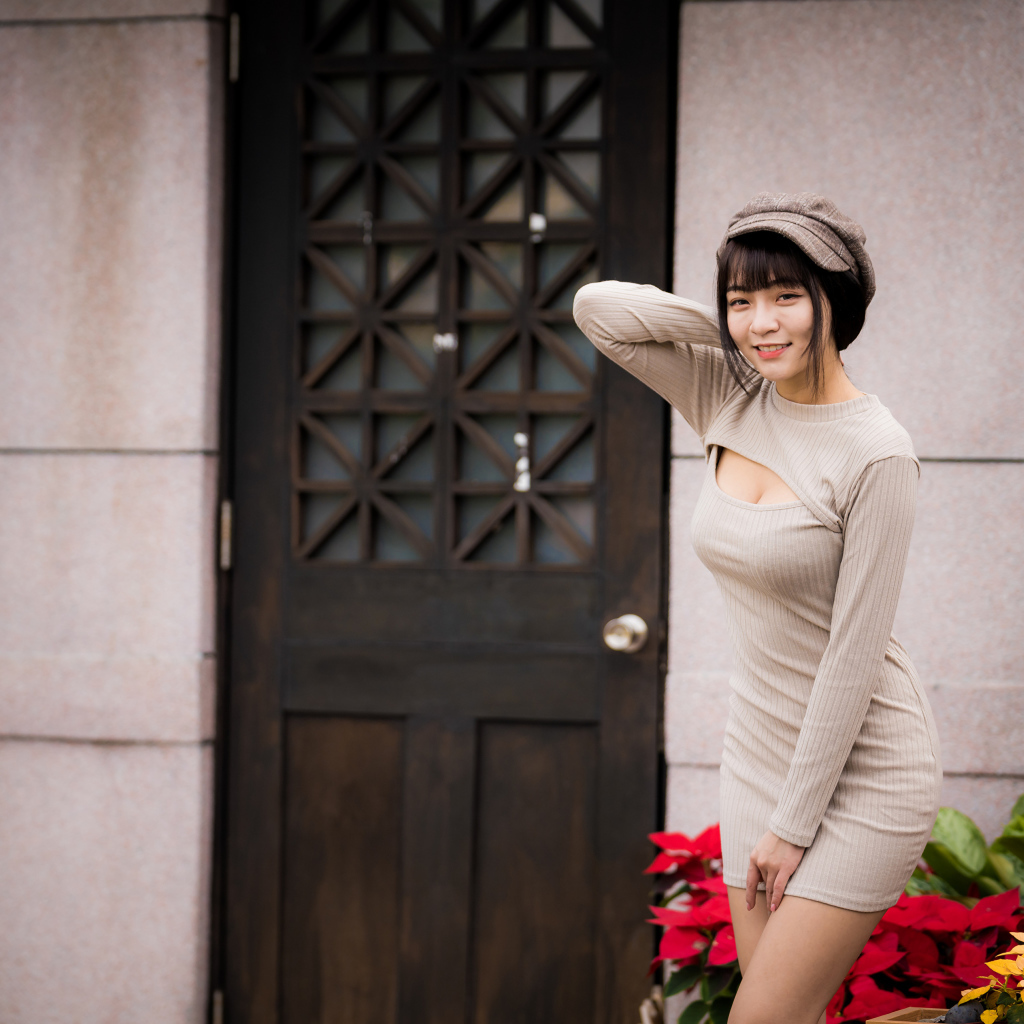 Красивая азиатка в платье стоит у двери 