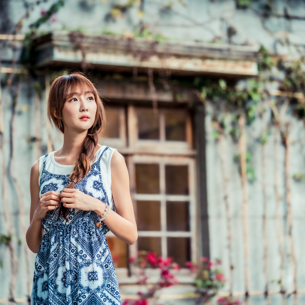 Красивая девушка азиатка в сарафане у старого дома 