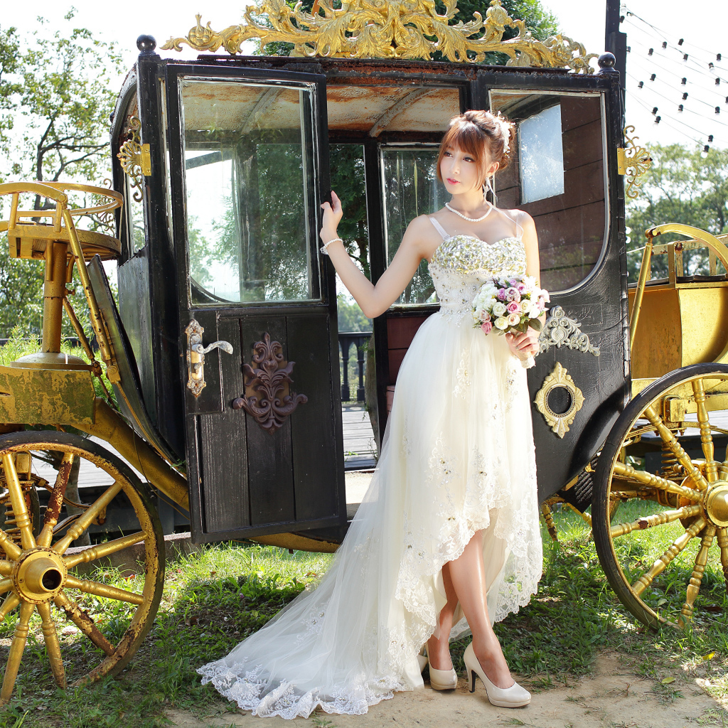 Красивая девушка азиатка в свадебном платье у кареты 