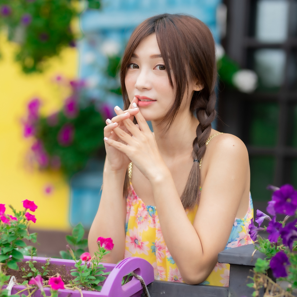 Красивая девушка Азиатка у цветов петунии