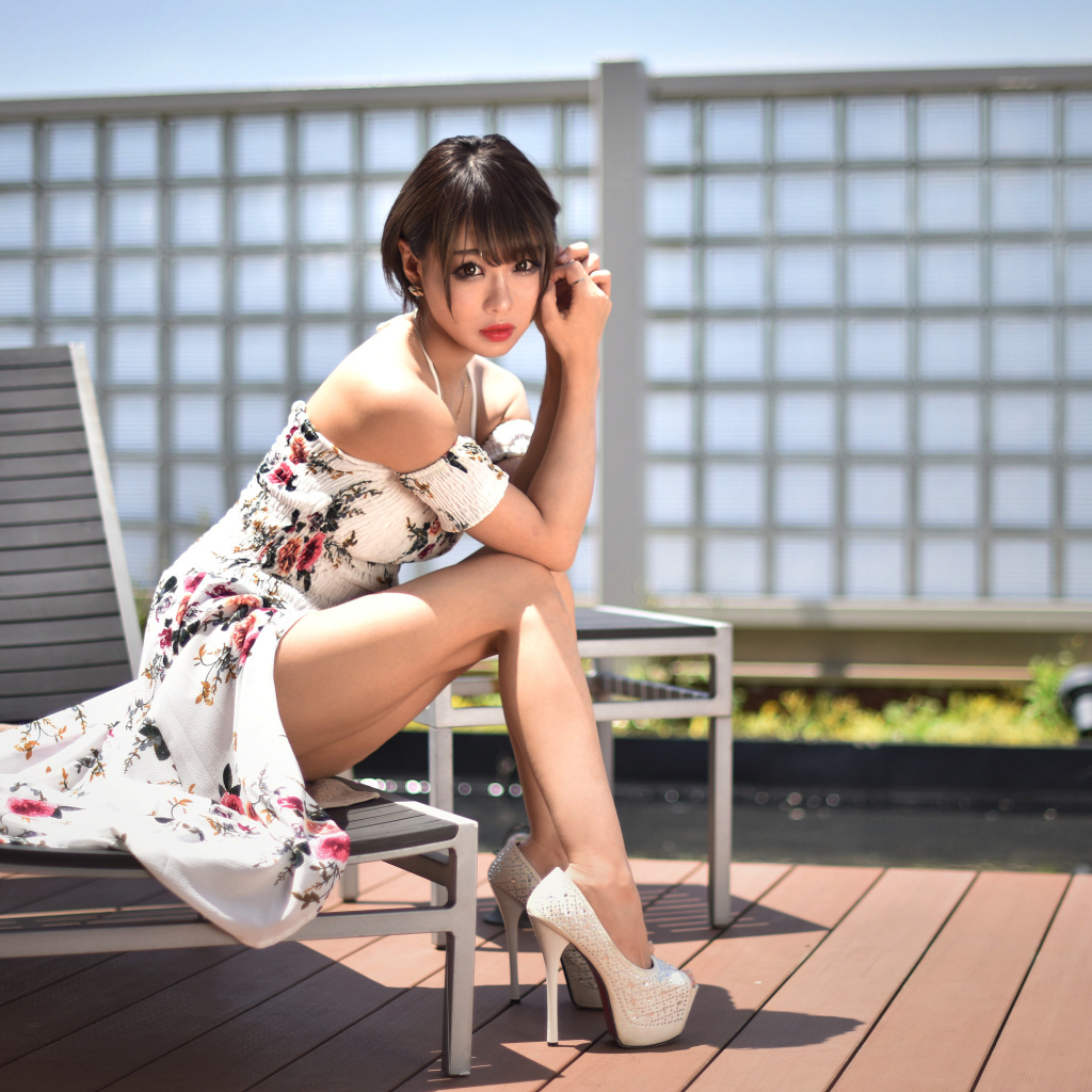 Красивая девушка азиатка сидит на шезлонге 