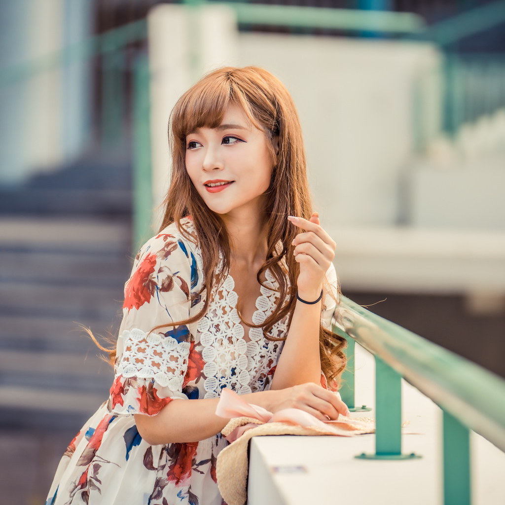 Красивая девушка азиатка стоит у перил 