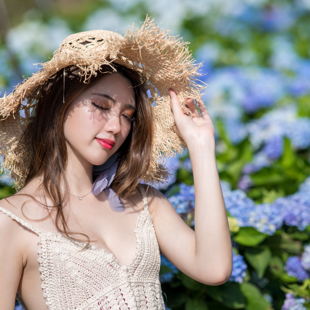 Красивая девушка азиатка с закрытыми глазами на фоне цветов гортензии