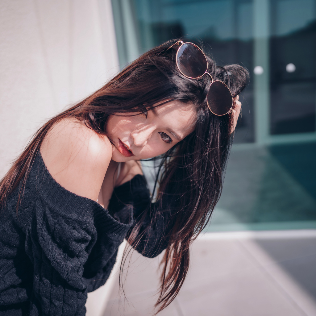 Красивая азиатка в черном свитере с солнечными очками на голове 