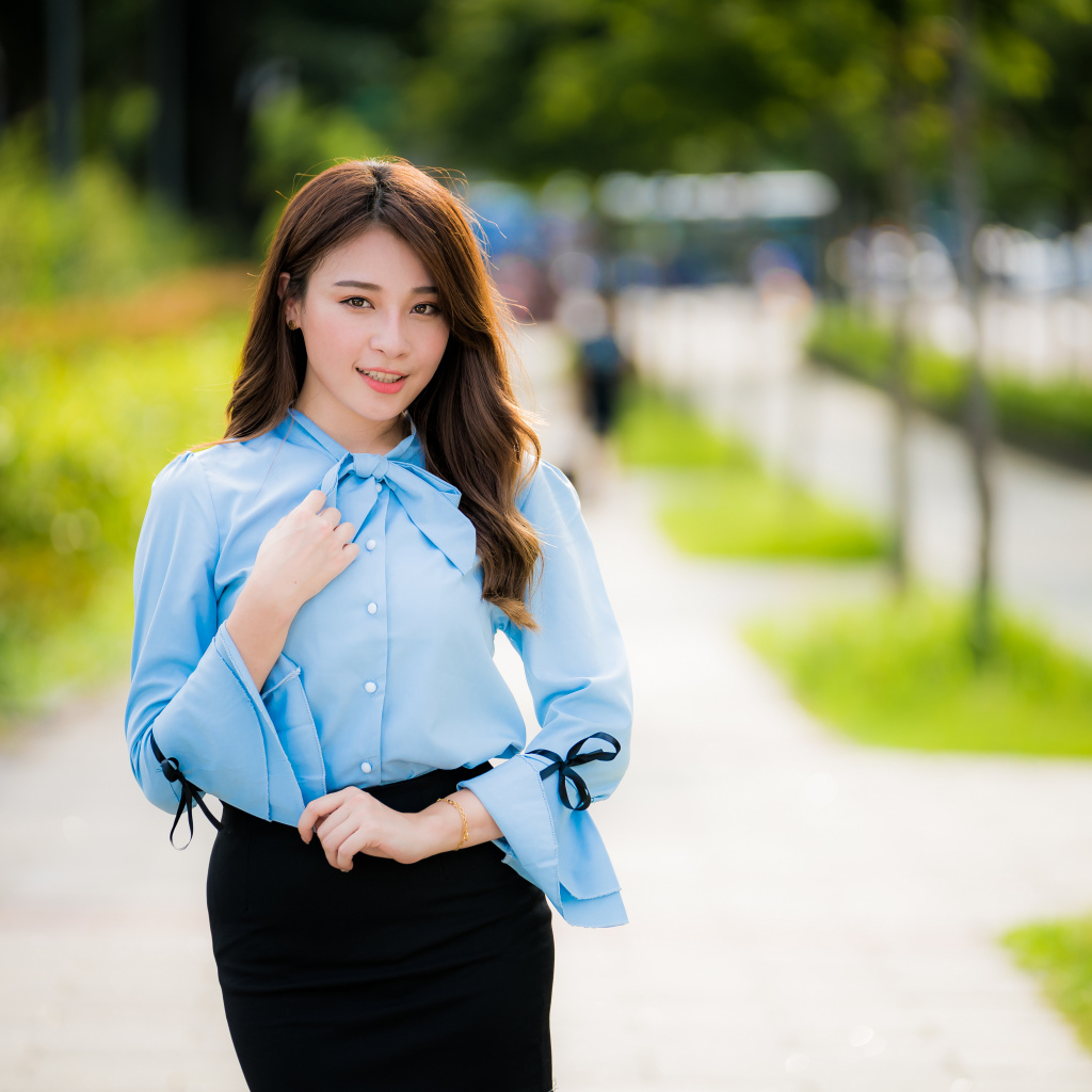 Красивая азиатка в голубой блузке и черной юбке 