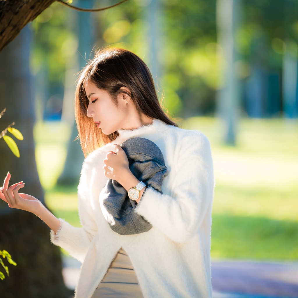 Красивая азиатка в белой кофте в солнечном парке