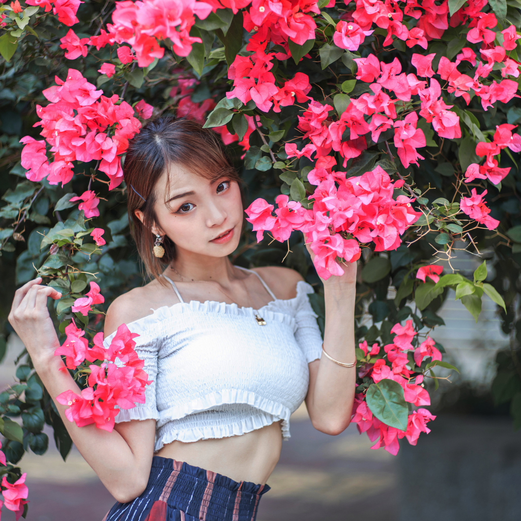 Красивая азиатка стоит у дерева с красными цветами