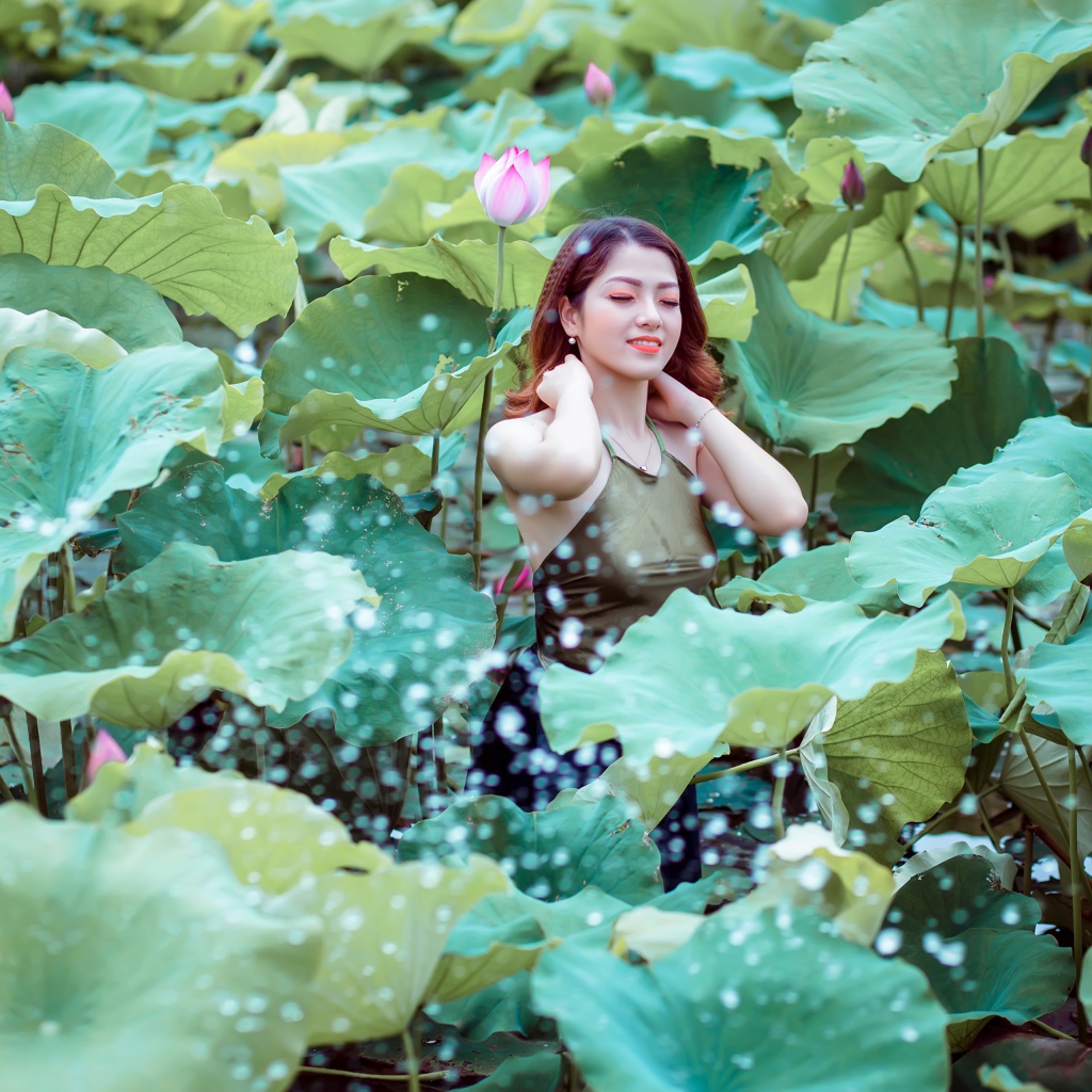 Красивая девушка азиатка в зеленых листьях лотоса 