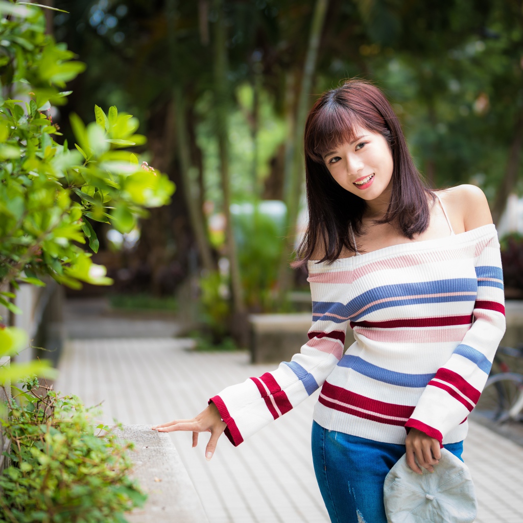 Красивая азиатка в полосатом свитере в парке