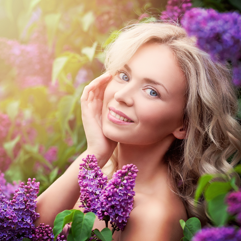 Красивая голубоглазая девушка блондинка в цветах сирени